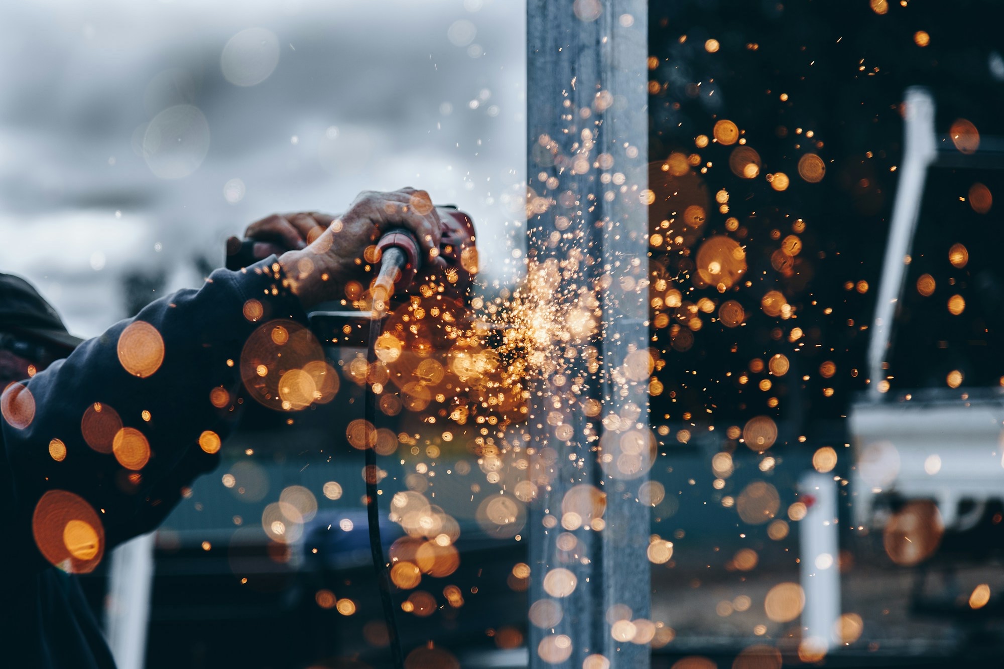 Close-up of metal being ground with orange sparks flying — surface prep work